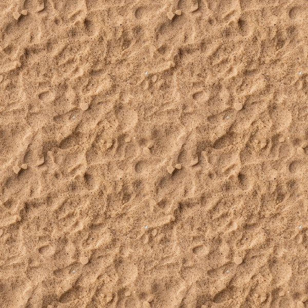 A close-up view of textured sand with small ripples and scattered pebbles.