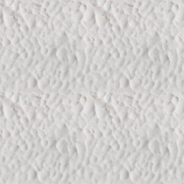 Close-up view of white sand with a pattern of small, uneven ridges and shallow depressions.