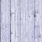Close-up of a weathered, white-painted wooden fence with vertical planks showing knots and grain patterns.